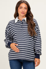 woman wearing a navy and gray striped maternity top with a white collar, holding her baby bump
