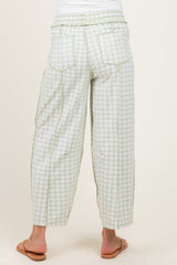 woman wearing light green and white gingham maternity pants with a relaxed fit and side pockets, shown from the back