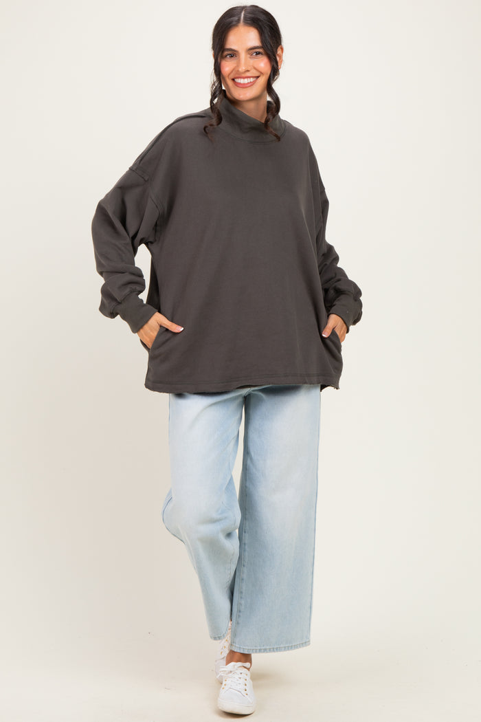 woman wearing an oversized dark gray sweatshirt with side pockets and light blue wide-leg jeans
