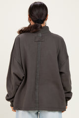 woman wearing an oversized dark gray pullover sweatshirt with a high collar and back seam detail