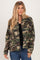 woman wearing a green camouflage button-up jacket over a black top, styled with blue jeans