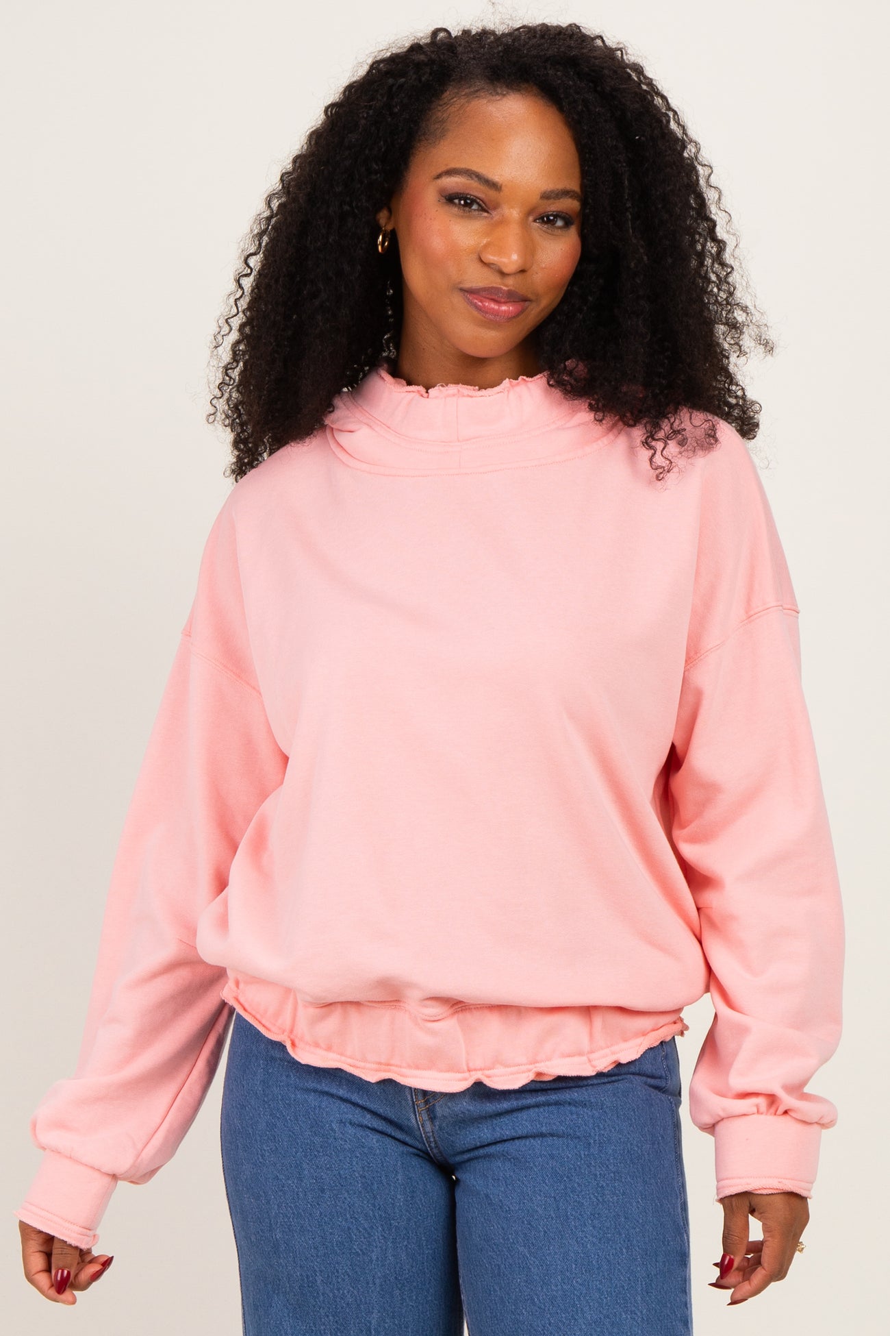 woman wearing a soft pink oversized sweatshirt with a ruffled collar and cuffed sleeves