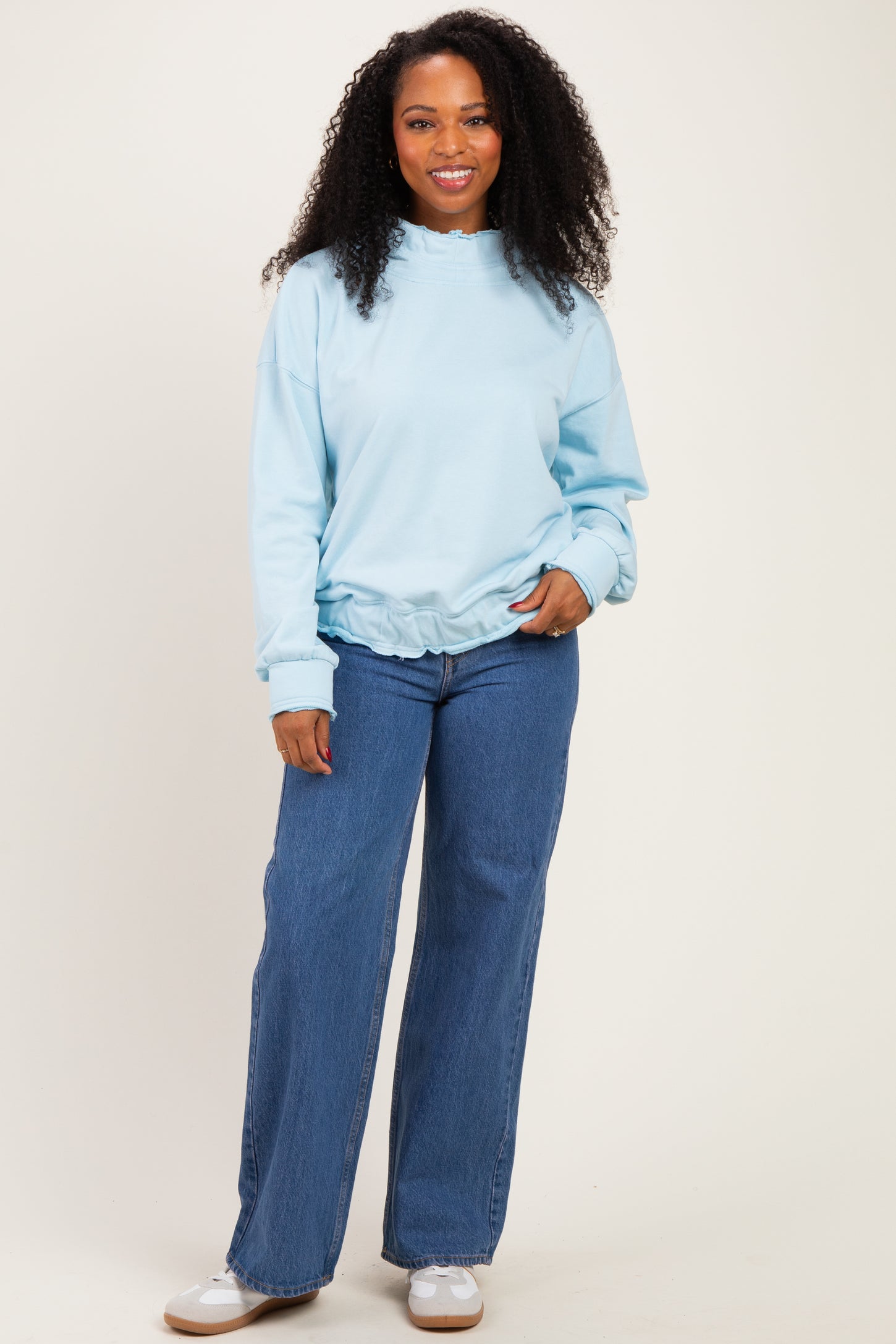 woman wearing a light blue oversized sweatshirt with a gathered hem and paired with wide-leg jeans