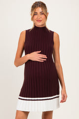 woman wearing a burgundy ribbed maternity dress with a sleeveless design and pleated white skirt, showing her baby bump