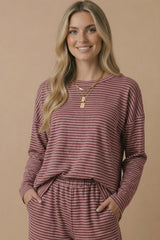woman wearing a maroon and white striped long sleeve top with pockets and matching bottoms, smiling at the camera