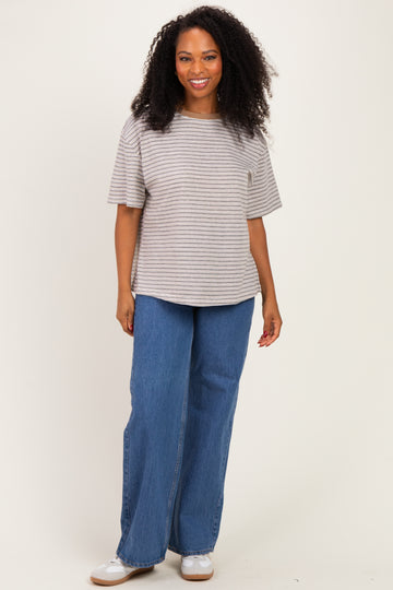 woman wearing a striped short sleeve top and wide leg blue jeans, smiling at the camera