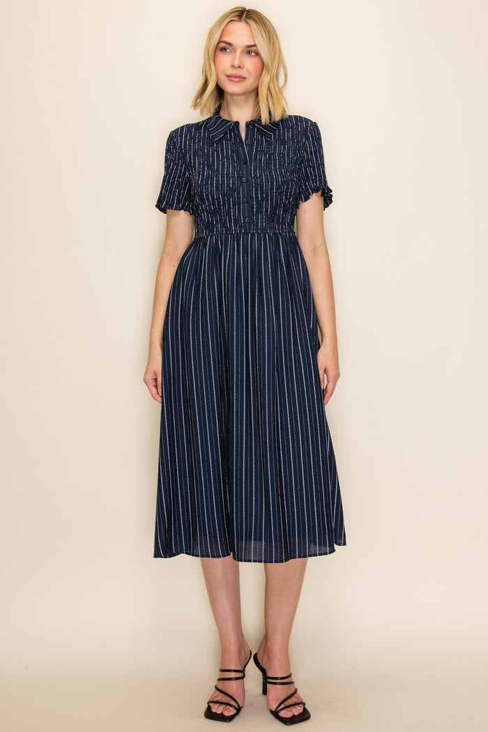 woman wearing a navy blue striped midi dress with a smocked waist and short sleeves