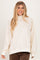 woman wearing a cream oversized sweatshirt with a floral print and high neck, styling it with brown corduroy pants