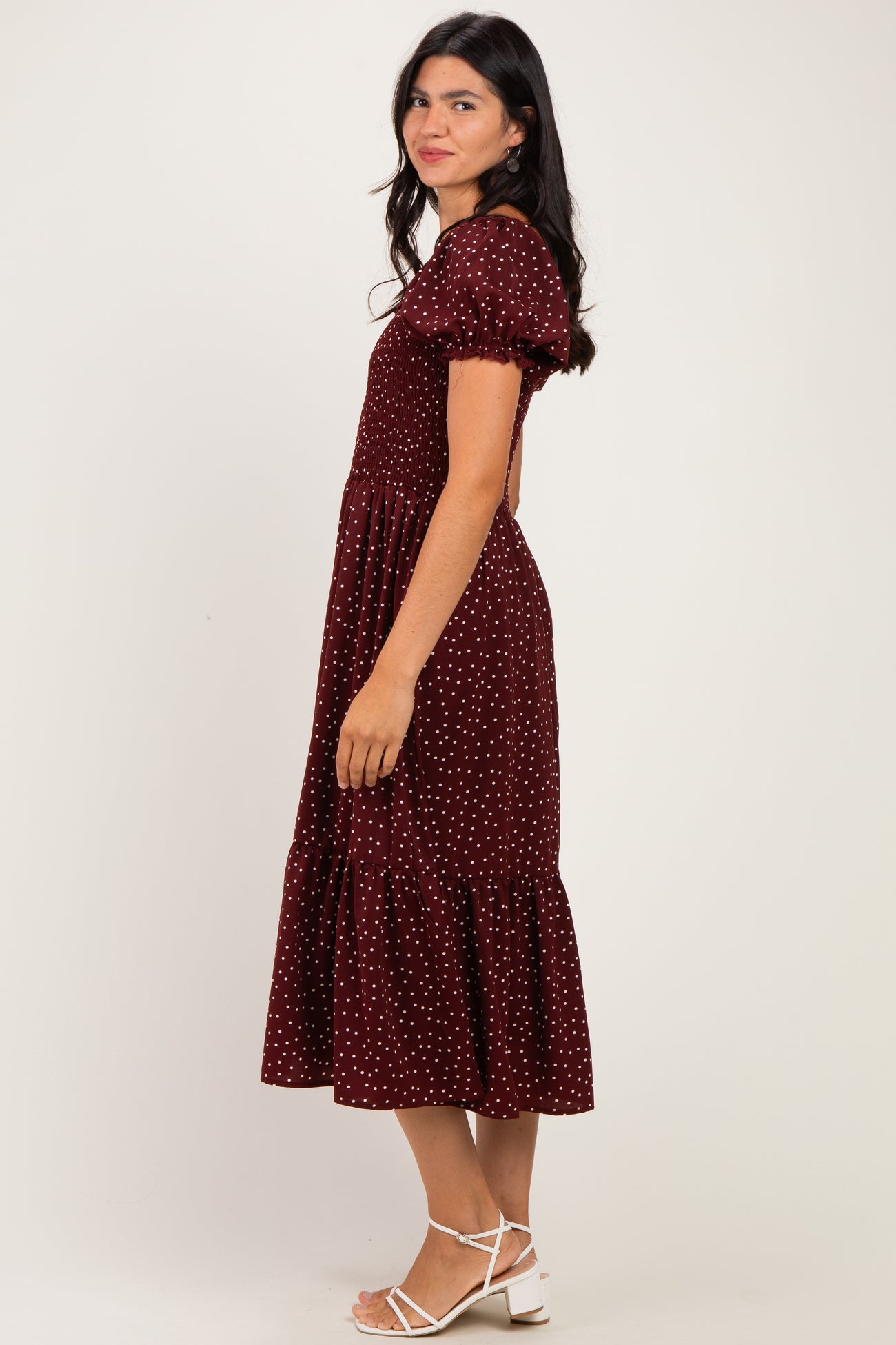 woman wearing a burgundy polka dot midi dress with puff sleeves and a ruffled hem
