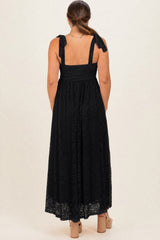 woman wearing a black lace maternity maxi dress with tie straps, showing a stylish back view