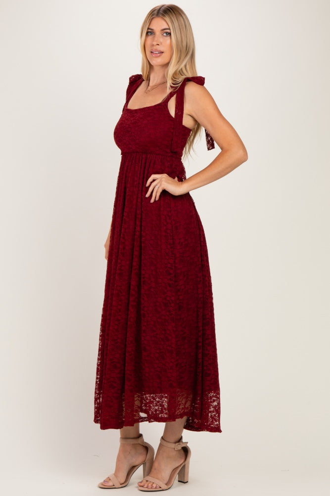 woman wearing a burgundy lace maxi dress with tie shoulder straps and a fitted bodice