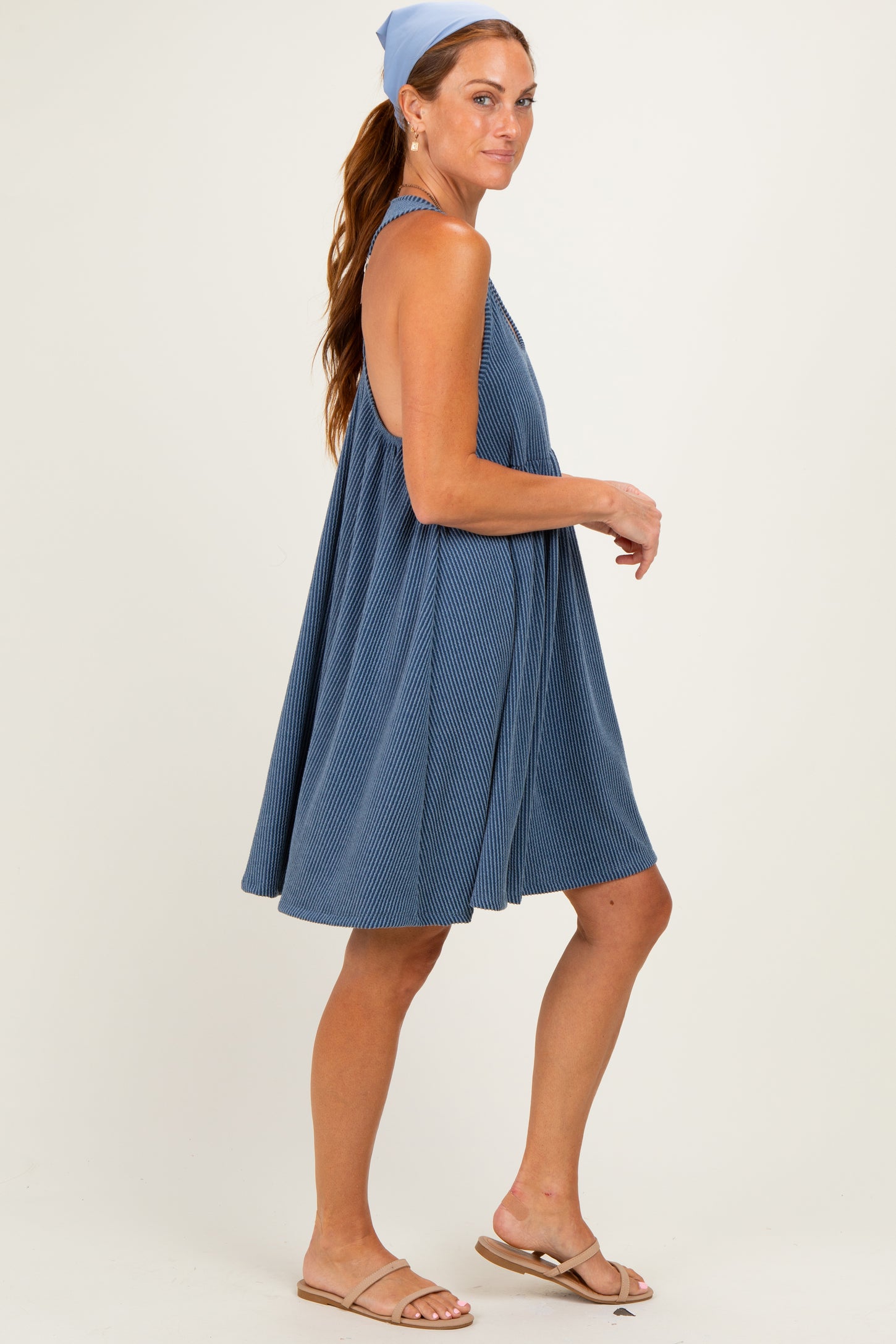 woman wearing a blue sleeveless swing dress with a textured fabric and sandals, styled with a light blue headband