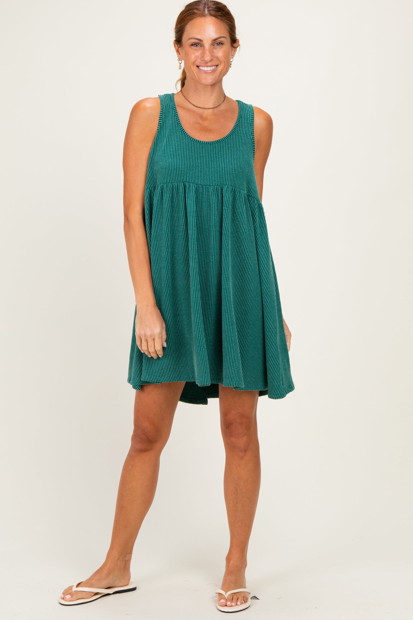 woman wearing a green striped tank dress with a flared skirt and white sandals