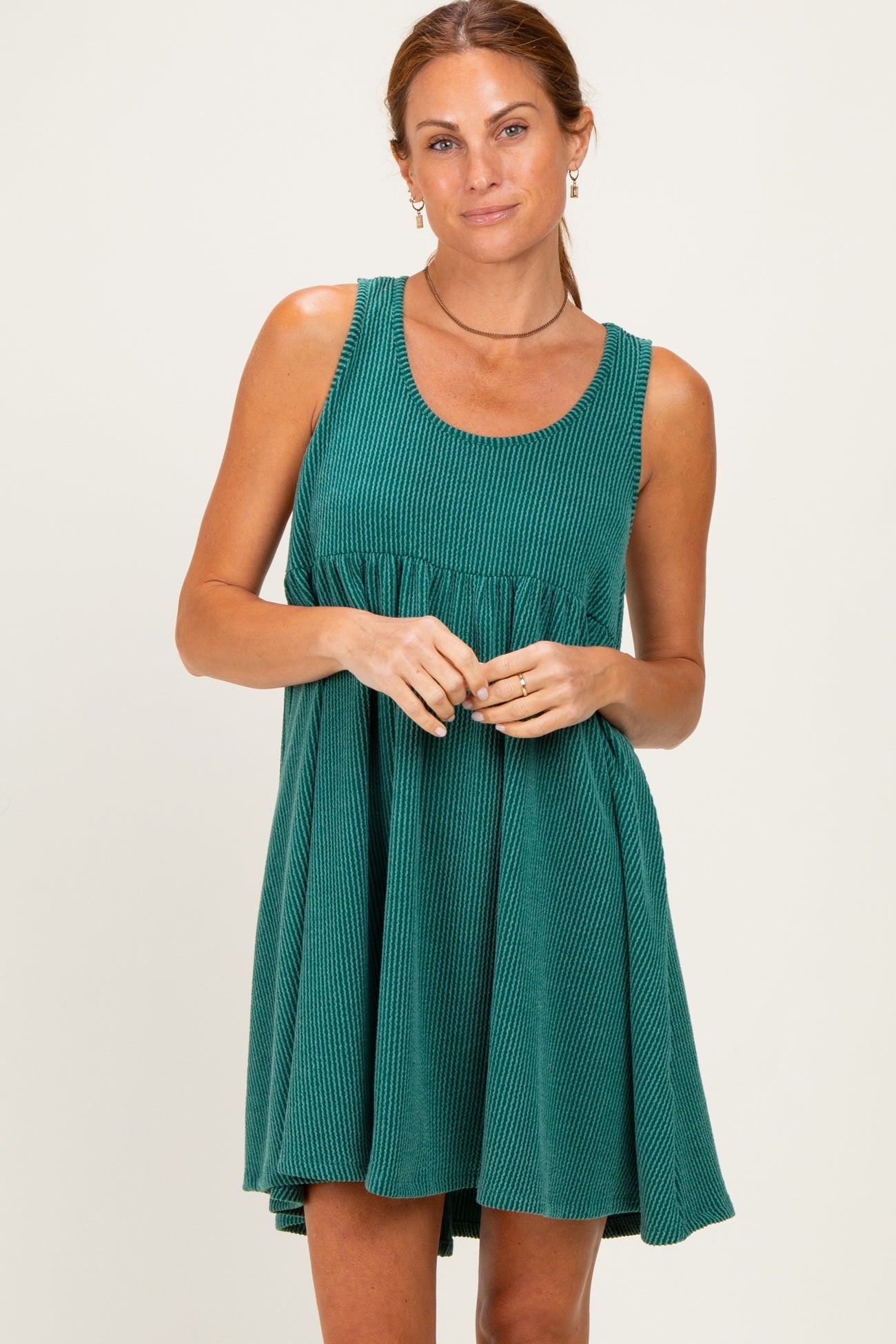 woman wearing a green ribbed sleeveless dress with a fitted bodice and flared skirt