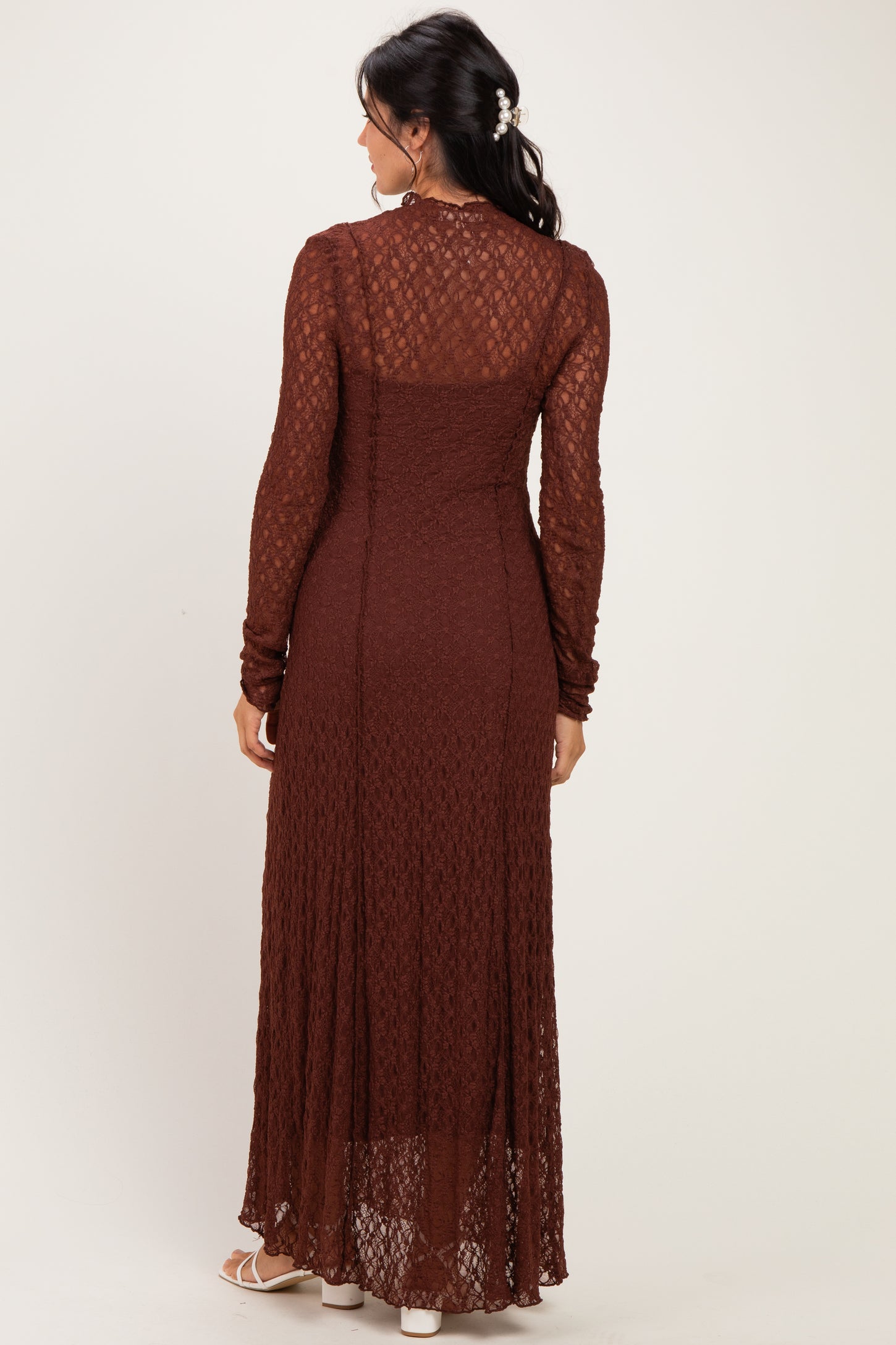 woman wearing a long rust-colored lace maxi dress with long sleeves and a fitted silhouette