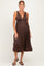 woman wearing a brown ribbed maternity dress with a deep V-neck and a flowing skirt, showcasing her baby bump