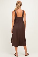 woman wearing a brown maternity dress with a flowing skirt and wide straps, viewed from the back