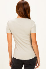 woman wearing a light gray ribbed short sleeve top, seen from the back, styled with dark jeans