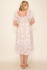 woman wearing a back view of a light pink floral midi dress with puff sleeves and a tiered skirt