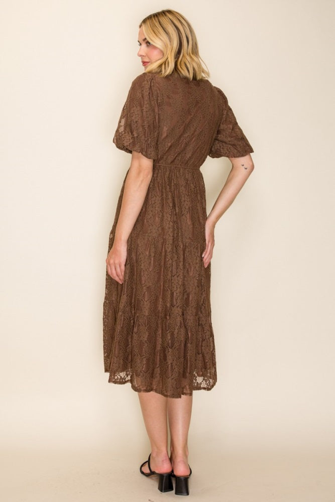 woman wearing a brown lace midi dress with short sleeves and a cinched waist, shown from the back