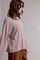 woman wearing a pink and white striped oversized polo shirt with long sleeves and a casual fit
