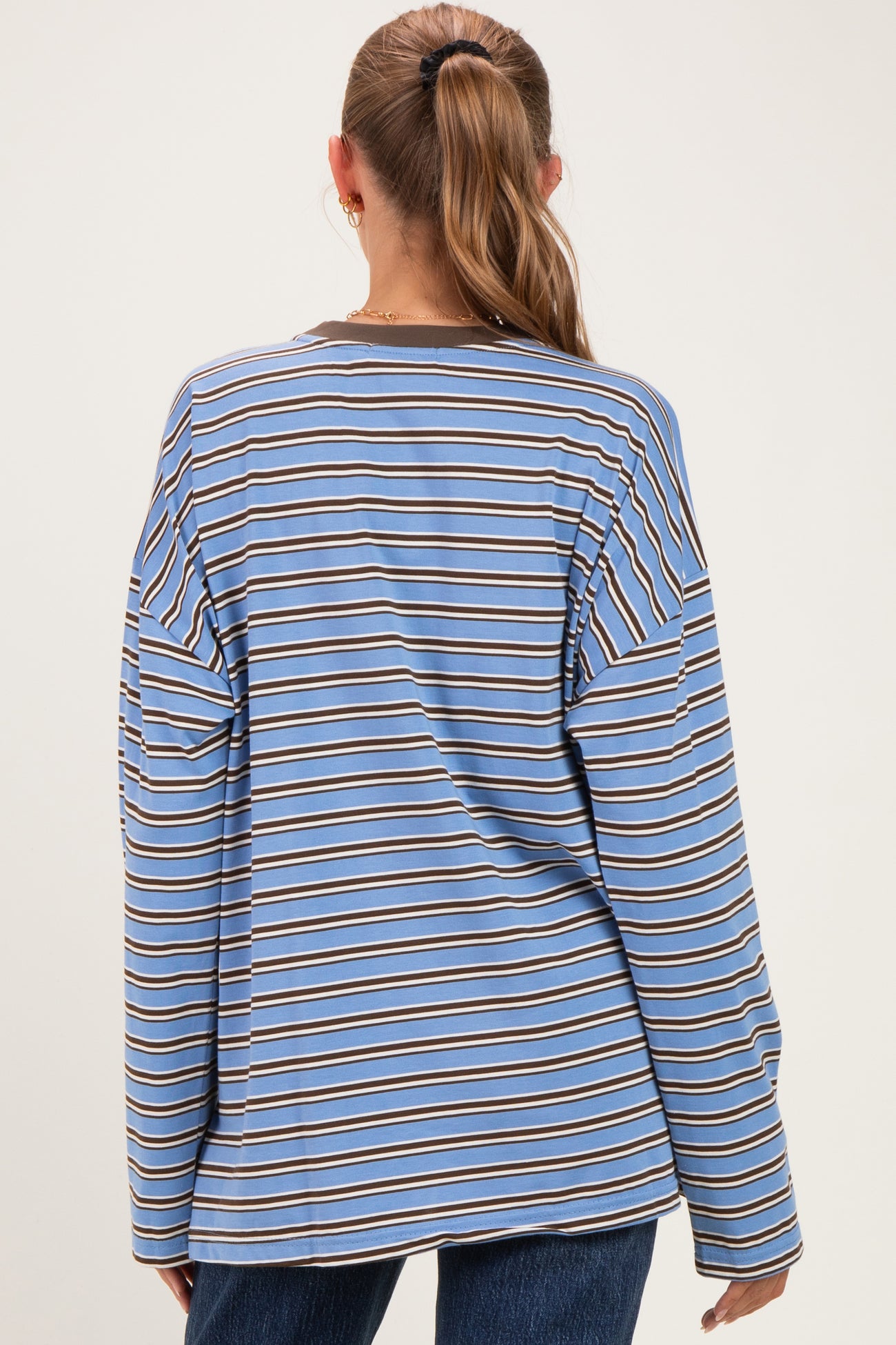 woman wearing a blue and brown striped maternity top with long sleeves, shown from the back