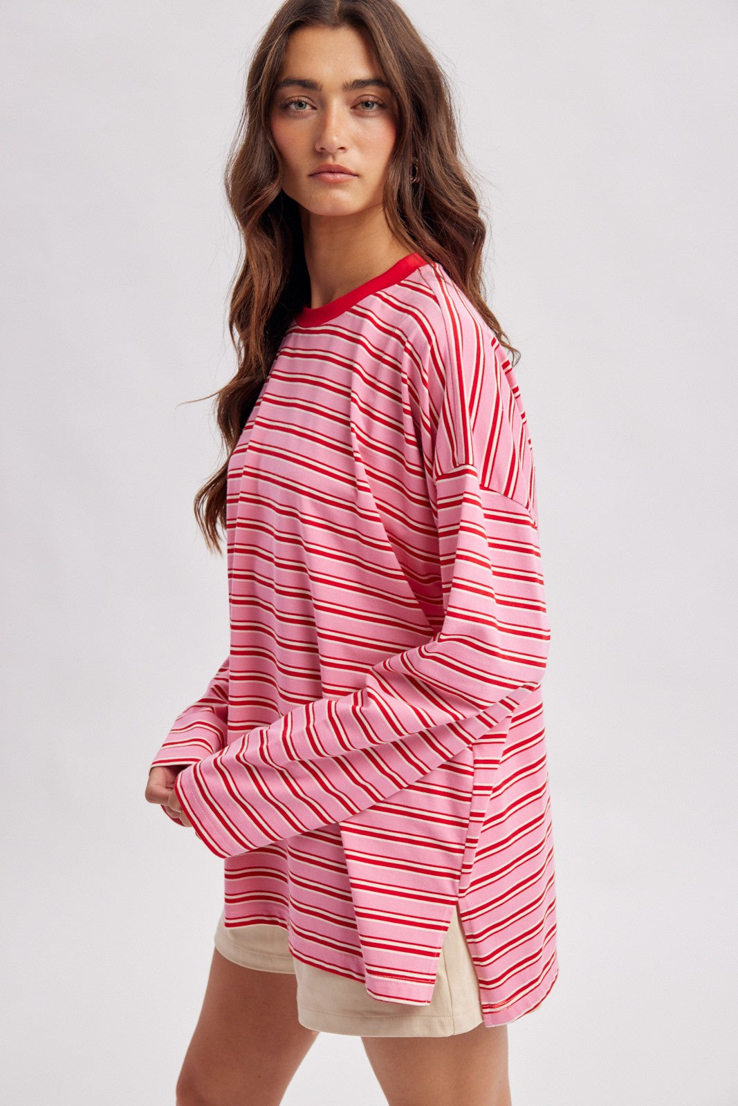 woman wearing a pink and red striped long sleeve top with a round neckline and relaxed fit