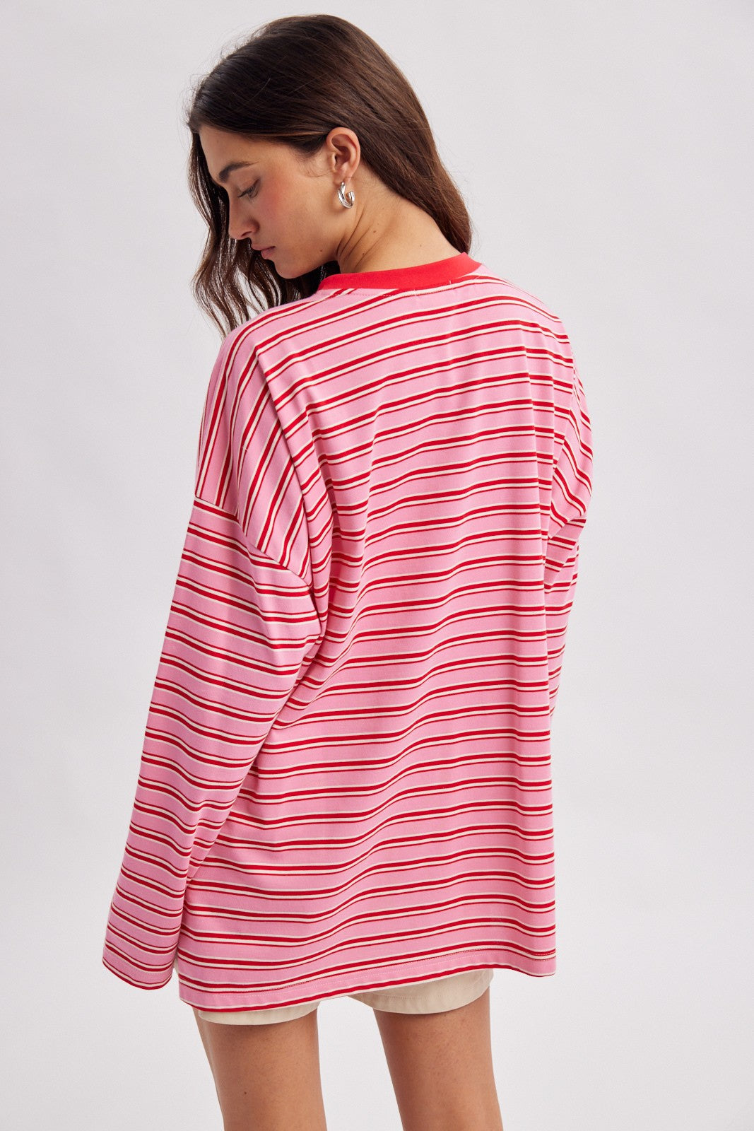 woman wearing a pink and white striped oversized long sleeve shirt with a round neckline