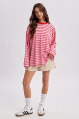 woman wearing a red and pink striped oversized sweatshirt with a crew neck, paired with beige shorts and white socks