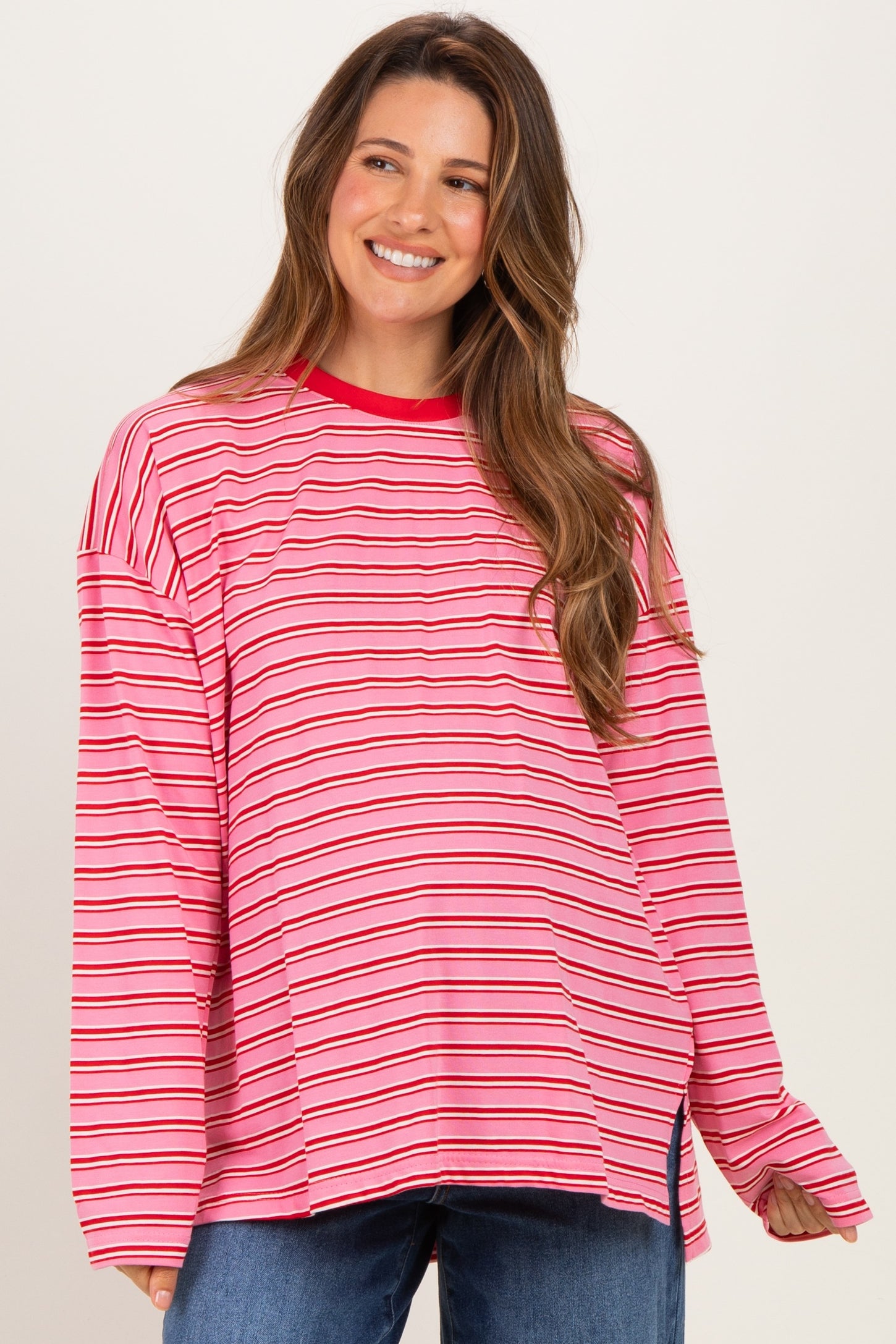 woman wearing a pink and red striped oversized maternity top with long sleeves and a relaxed fit