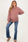 woman wearing a dusty rose oversized maternity sweatshirt and blue flared jeans, with a visible baby bump