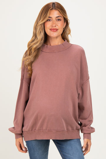 woman wearing a mauve maternity oversized sweatshirt with a high neckline and relaxed fit, showcasing her baby bump