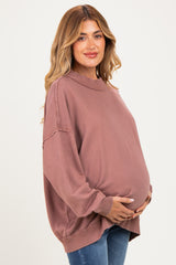 woman wearing a dusty rose oversized maternity sweatshirt and holding her baby bump