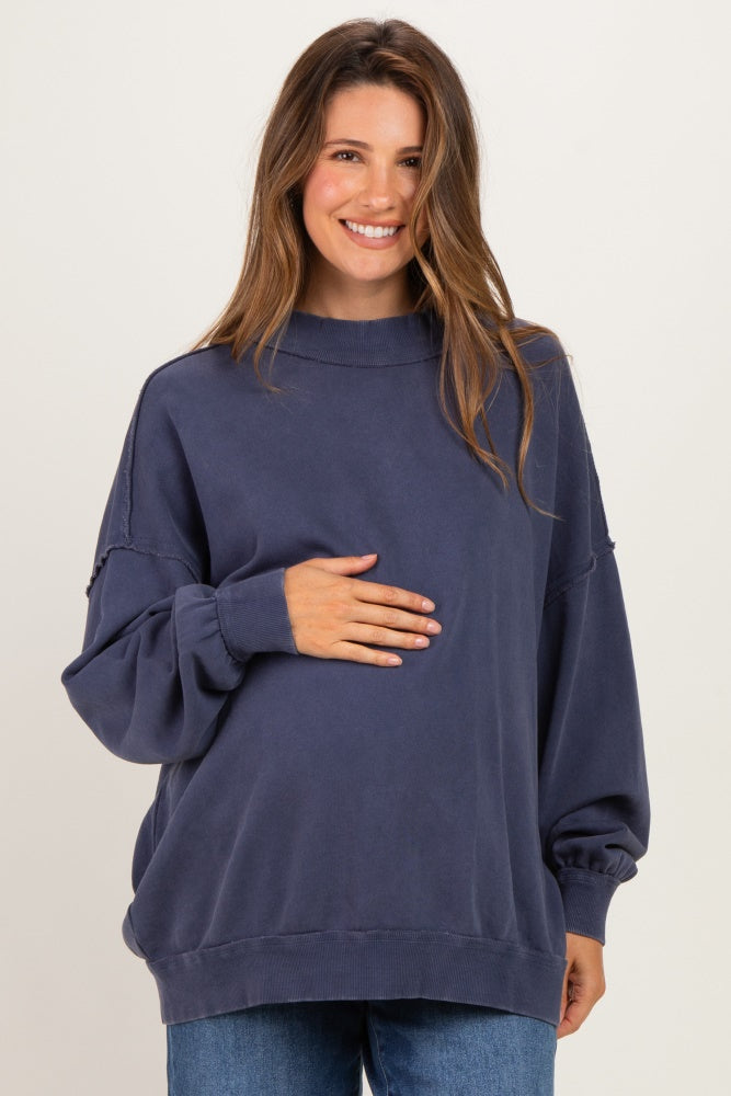 woman wearing a navy blue oversized maternity sweatshirt and holding her baby bump