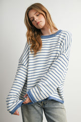 woman wearing a light blue and white striped oversized sweater with long sleeves and a relaxed fit