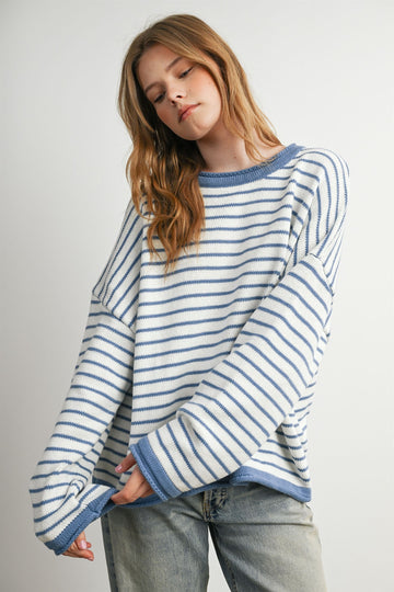 woman wearing a light blue and white striped oversized sweater with long sleeves and a relaxed fit