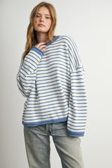 woman wearing a white and blue striped oversized sweater with a crew neck and dropped shoulders, paired with light blue jeans