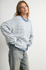 woman wearing a light blue and white striped oversized sweater with long sleeves and relaxed fit, paired with jeans