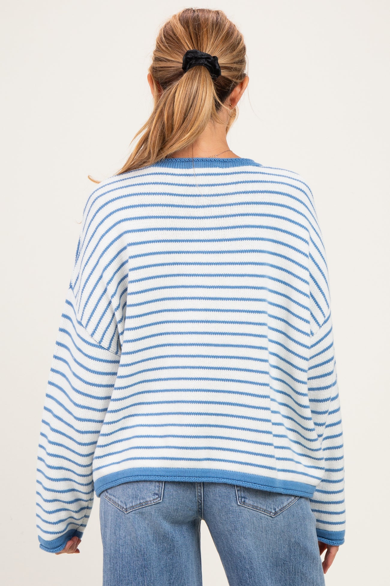 woman wearing a striped blue and white maternity sweater with a relaxed fit and back view shown