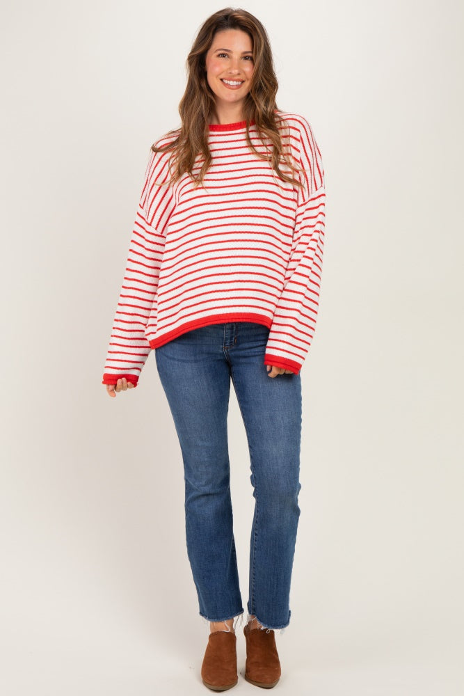 woman wearing a red and white striped maternity sweater with a relaxed fit, paired with blue jeans