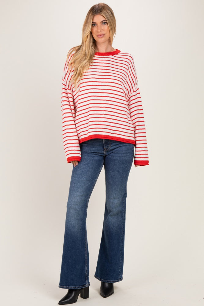 woman wearing a red and white striped oversized sweater with flared jeans and black ankle boots