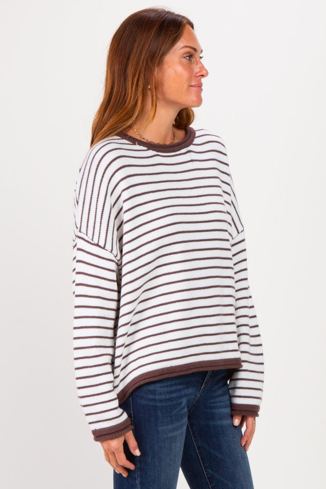 woman wearing a white and brown striped oversized sweater paired with blue jeans