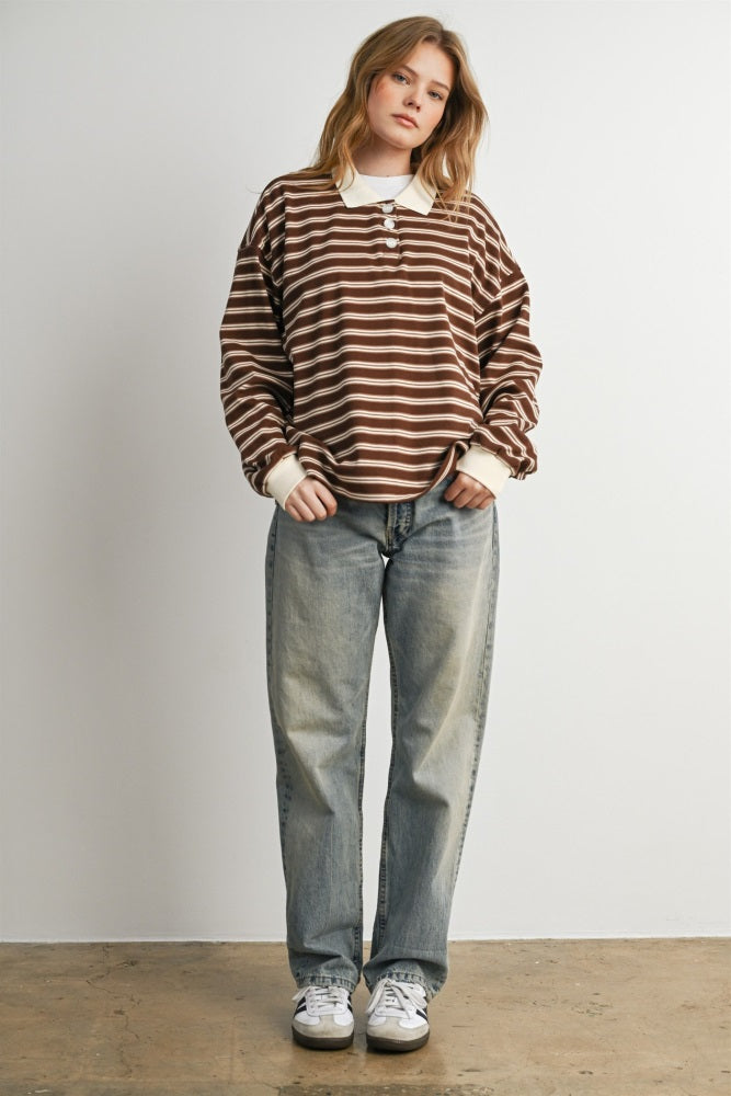 woman wearing a brown and cream striped long sleeve polo shirt and light blue baggy jeans