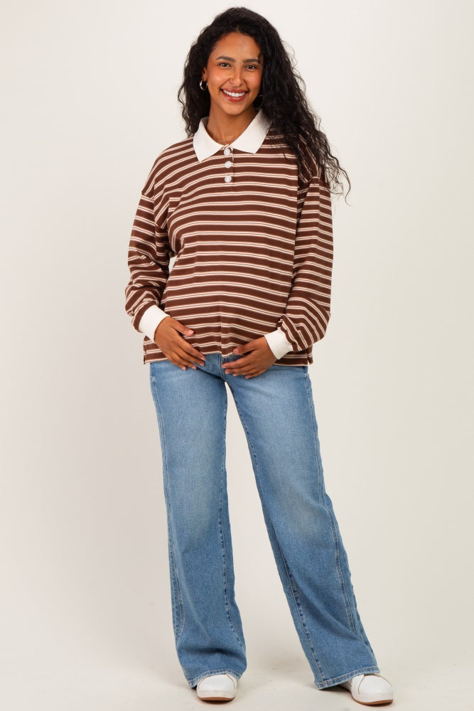 woman wearing a brown and white striped maternity polo shirt with a baby bump, paired with light blue flared jeans