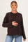 woman wearing a brown polka dot maternity top and holding her baby bump