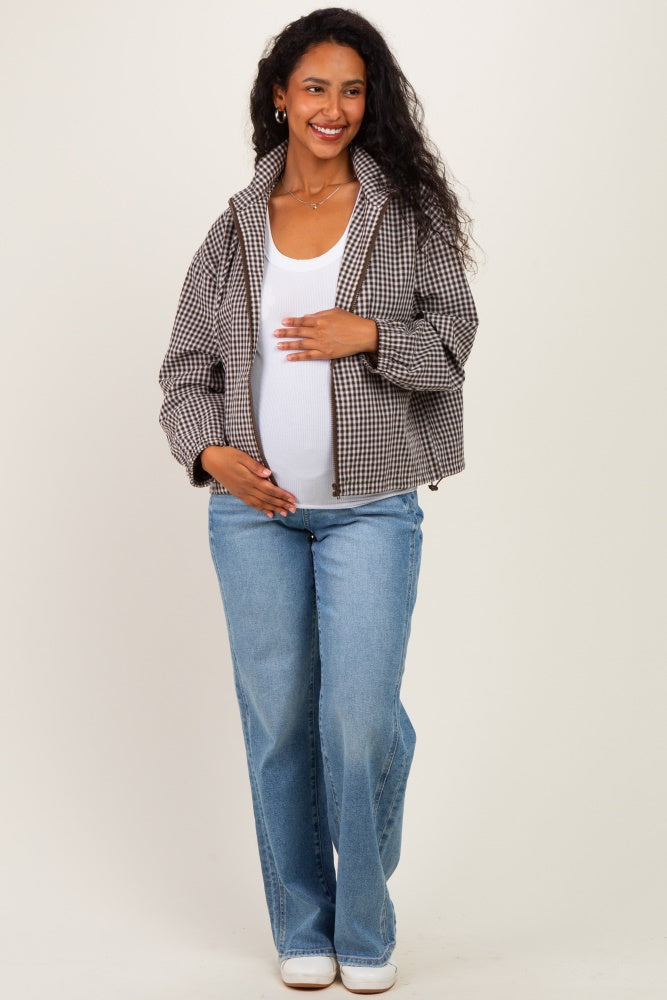 woman wearing a brown and white checkered maternity jacket, white tank top, and light blue jeans with a visible baby bump