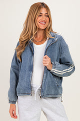 woman wearing a blue denim maternity jacket with white stripes and a white top, smiling and holding the jacket open