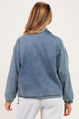 woman wearing a light blue oversized denim jacket, styled for maternity wear, showing the back view