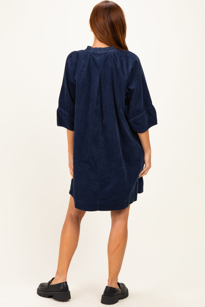 woman wearing a navy corduroy shirt dress with three-quarter sleeves and a relaxed fit, viewed from the back