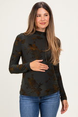 woman wearing a dark green floral long sleeve maternity top and holding her baby bump